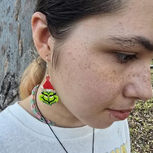 Puede incluir: Pendientes hechos a mano con cuentas que representan la cara del Grinch. Los pendientes tienen una cara verde, un gorro de Pap&aacute; Noel rojo y ganchos plateados. Un accesorio festivo para la temporada navide&ntilde;a.