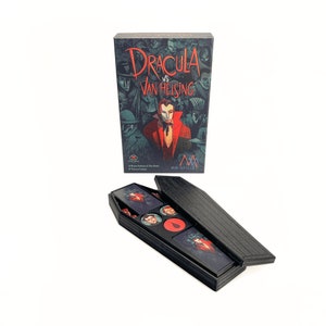 Könnte beinhalten: Eine schwarze Sarg-förmige Box mit einem offenen Deckel, der ein Spielbrett und Spielfiguren enthüllt. Die Box hat eine Holzmaserung. Der Deckel trägt den Titel "Dracula vs Van Helsing" in Rot und Weiß.