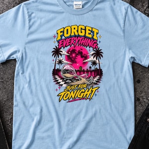 May include: A light blue t-shirt featuring a graphic print of a pink moon, palm trees, and a tipped hourglass. The text reads "FORGET EVERYTHING" in yellow and "JUST FOR TONIGHT" in yellow, with a black and white checkered pattern at the base.