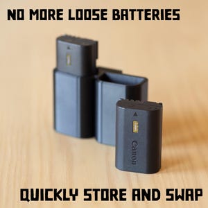 May include: Black Canon camera batteries and storage cases are displayed on a wooden surface. The text "NO MORE LOOSE BATTERIES" and "QUICKLY STORE AND SWAP" are printed in bold, black letters. The image showcases a practical solution for organizing camera batteries.