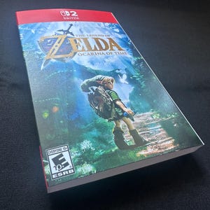 May include: A rectangular video game case for The Legend of Zelda: Ocarina of Time for Nintendo Switch. The cover features a green-clad character standing on a path in a forest, the game title in gold text, and an ESRB Everyone 10+ rating logo.