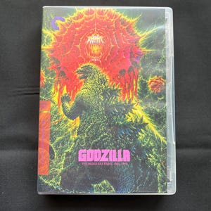 May include: A rectangular Blu-ray case featuring a vibrant illustration of Godzilla in green and black, standing before a large, glowing red and orange organic structure. The text reads Godzilla The Heisei-Era Films, 1984-1995 in pink letters.