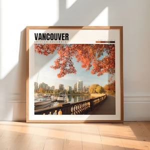 May include: A framed print of a cityscape with a waterfront and boats. The city is in the background and the foreground shows a stone walkway with a railing. The sky is blue and there are trees with red leaves in the foreground. The print has the text "VANCOUVER BRITISH COLUMBIA" and coordinates at the top.