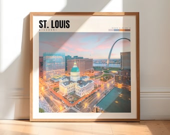 May include: A framed print of an aerial view of St. Louis, Missouri, featuring the Gateway Arch and the Old Courthouse. The print has a light blue, pink, and orange color scheme with a white background. The text "ST. LOUIS" and "MISSOURI" is printed in black at the top of the print.