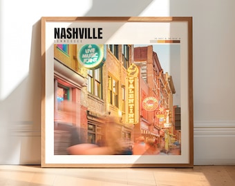 May include: A framed print of a street scene in Nashville, Tennessee. The image features a vibrant, colorful street with neon signs, including "A Live Music Joint" and "The Valentine". The street is bustling with people, and the buildings are brick with a warm, inviting atmosphere.