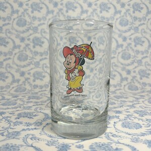 May include: A clear glass drinking glass with a cartoon image of Minnie Mouse wearing a red hat and holding an umbrella. The text "&copy; Walt Disney Productions" is printed on the glass.