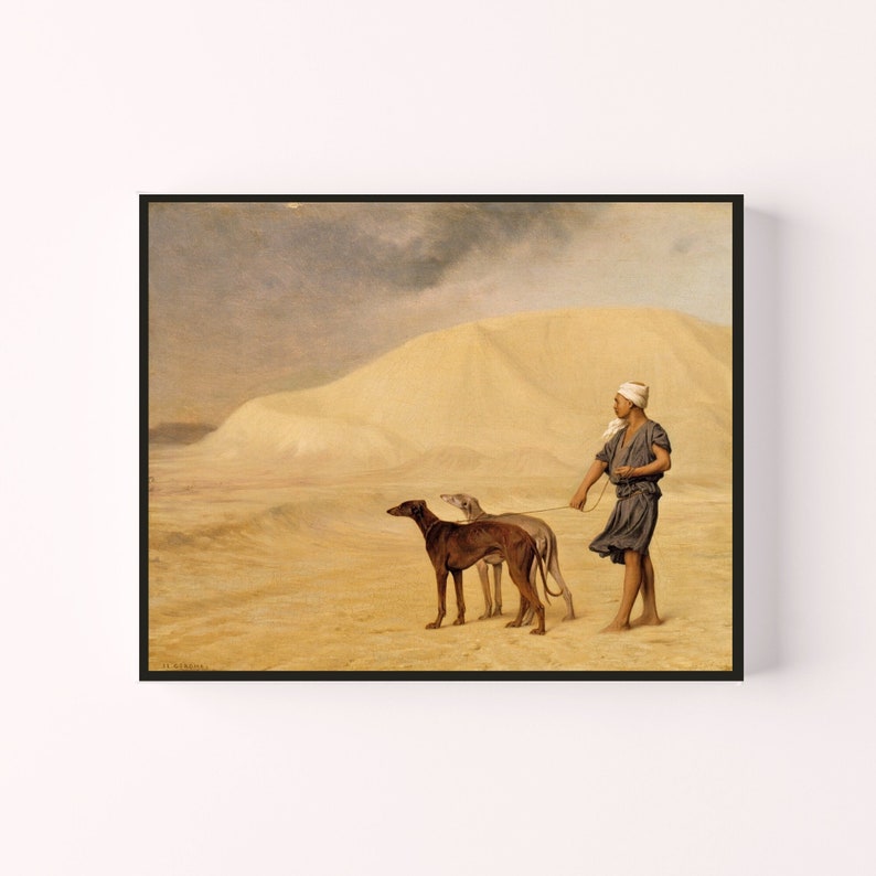 Op de afbeelding: Ingelijste prent van een antiek schilderij dat een persoon afbeeldt die twee slanke honden door een woestijnlandschap leidt. De persoon draagt een hoofdbedekking en een donkerblauw gewaad. De honden zijn bruin en grijs.