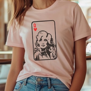 Peut inclure: T-shirt rose clair avec un motif de carte &agrave; jouer. La carte repr&eacute;sente un portrait de femme et la lettre "Q" avec un c&oelig;ur rouge. Le graphisme est en noir et blanc.