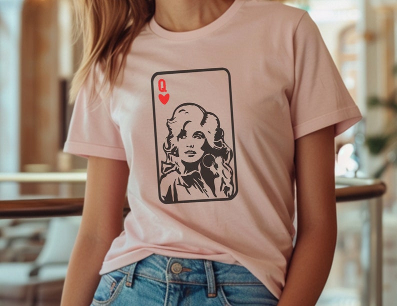 Peut inclure: T-shirt rose clair avec un motif de carte &agrave; jouer. La carte repr&eacute;sente un portrait de femme et la lettre "Q" avec un c&oelig;ur rouge. Le graphisme est en noir et blanc.