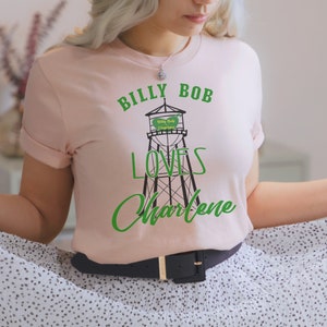 May include: A pink t-shirt with a green graphic of a water tower with the text "Billy Bob Loves Charlene" on it.