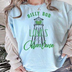 May include: A light blue t-shirt with a graphic of a water tower that says "Billy Bob Charlene" and the text "Billy Bob Loves Charlene".