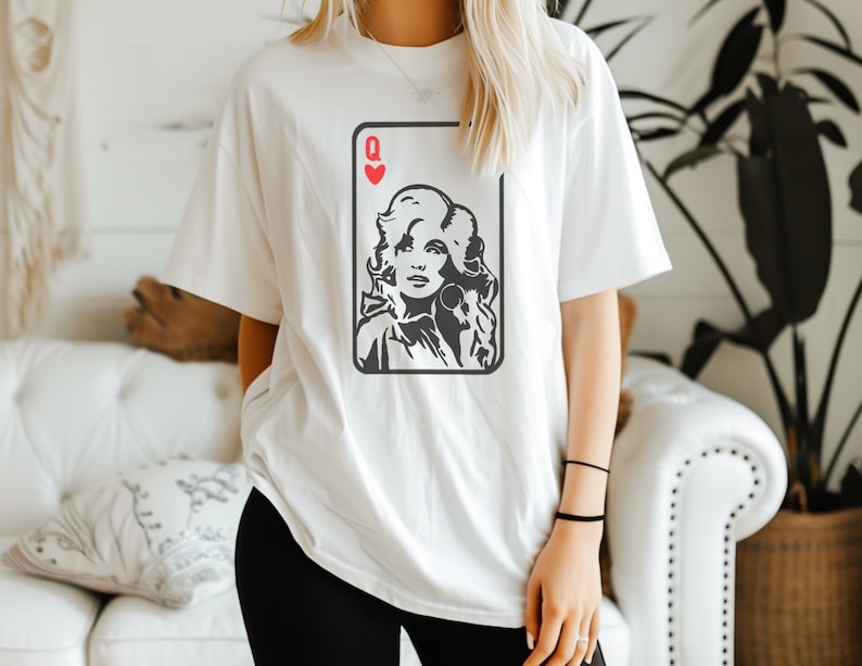Peut inclure: T-shirt blanc avec un motif noir et blanc d'une carte &agrave; jouer, la Dame de C&oelig;ur. L'image de la reine est un portrait d'une femme aux cheveux blonds. Le t-shirt est de coupe ample et d&eacute;contract&eacute;e.