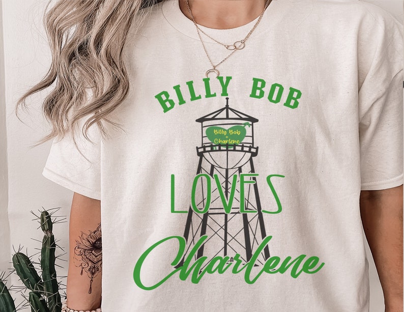 May include: White t-shirt with a green and black graphic of a water tower with the text "Billy Bob Loves Charlene" and a heart that says "Billy Bob Charlene".
