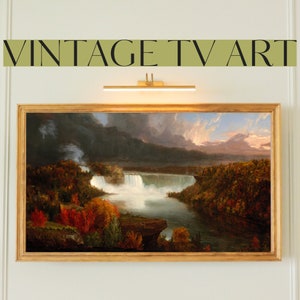 May include: A framed painting of a waterfall in a forest setting. The painting is in a gold frame and has a vintage aesthetic.
