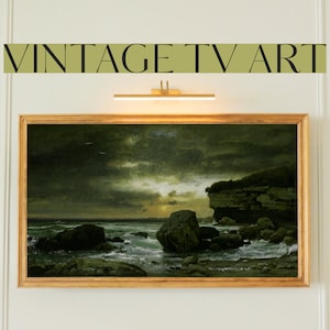 May include: A framed painting of a seascape with a rocky shore and a stormy sky. The painting is in a gold frame and is lit by a light fixture above.