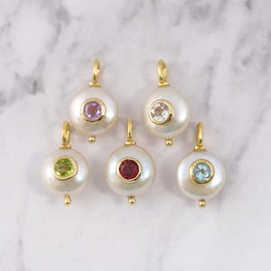 May include: Five round white pearl pendants with gold-tone metal settings. Each pendant features a small, circular faceted gemstone in the center, including light purple, clear, lime green, deep red, and light blue stones with gold loops.