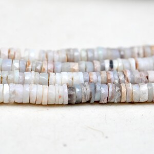 Pu&ograve; includere: Un filo di perle di opale bianco con forma irregolare e sfaccettata. Le perle misurano circa 4 mm e hanno un leggero bagliore iridescente.