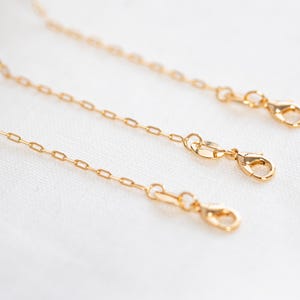 May include: Three gold chain extenders with lobster claw clasps. The chains are different lengths.