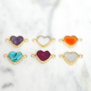 Pu&ograve; includere: Sei ciondoli dorati a forma di cuore con pietre preziose di diversi colori. I ciondoli hanno due anelli su entrambi i lati per essere attaccati ai gioielli.