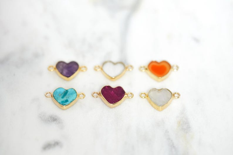 Pu&ograve; includere: Sei ciondoli dorati a forma di cuore con pietre preziose di diversi colori. I ciondoli hanno due anelli su entrambi i lati per essere attaccati ai gioielli.