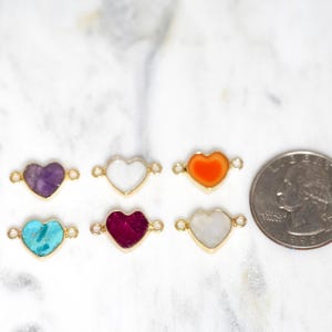 Pu&ograve; includere: Sei ciondoli a forma di cuore con pietre di diversi colori, tra cui viola, bianco, arancione, turchese, rosso e bianco. I ciondoli sono circa delle dimensioni di una moneta da 25 centesimi di dollaro americano.