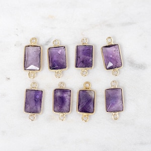 May include: Eight amethyst gemstone connectors with gold-toned metal accents. Each connector has two loops for attaching to jewelry.