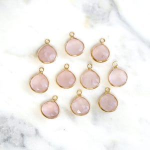May include: Twelve gold-tone pendants with rose quartz stones. Each pendant is shaped like a teardrop.