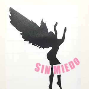 May include: Black silhouette of an angel with wings spread, falling with the Spanish words "SIN MIEDO" in pink letters below.