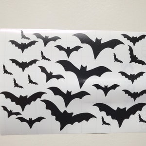 May include: A sheet of black bat stickers on a white background. The bats are of various sizes and are arranged in a random pattern.