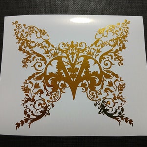 May include: Gold vinyl decal of a butterfly with intricate floral designs. The butterfly has a stylized letter "V" in the center.