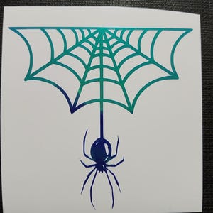 May include: A white sticker featuring a teal and blue gradient spider web design with a spider hanging below. The spider and web are outlined in a gradient of teal and blue.