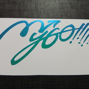 May include: A white sticker with the word "ygo!!!!" in a teal to green gradient. The word is written in a stylized, cursive font with multiple exclamation points.