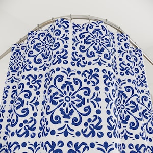May include: A white shower curtain with a blue and white geometric pattern. The pattern features intricate floral designs and swirls.