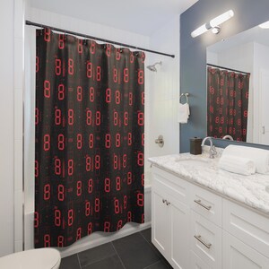 May include: A black shower curtain with a repeating pattern of red 8s. The shower curtain is in a bathroom with a white vanity and a mirror.