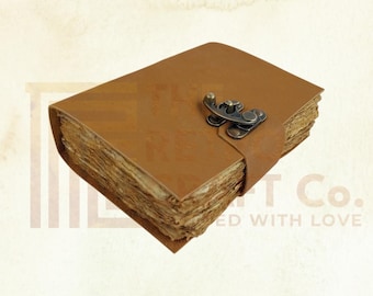 May include: A brown leather-bound journal with a brass clasp. The journal is closed and has a rustic, vintage look.