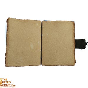May include: An open, blank journal with brown paper covers and a leather strap closure. The journal is made of recycled paper and has a rustic, vintage look.