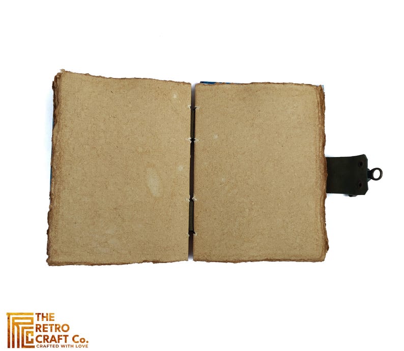 May include: An open, blank journal with brown paper covers and a leather strap closure. The journal is made of recycled paper and has a rustic, vintage look.