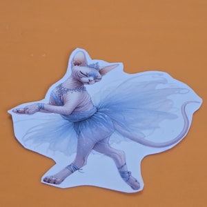 May include: A whimsical sticker featuring a Sphynx cat in a light blue tutu and ballet slippers. The cat is adorned with a delicate silver tiara and necklace. The sticker has a white border and is set against an orange background.