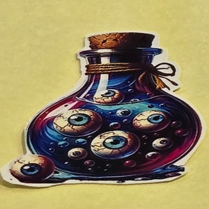 May include: A sticker featuring a potion bottle filled with blue and red liquid and multiple eyeballs. The bottle has a cork stopper and is tied with twine. The sticker is on a yellow background.