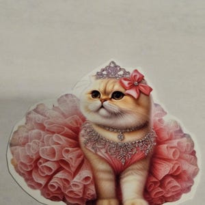 May include: A sticker featuring a cartoon cat wearing a pink tutu, a jeweled necklace, and a tiara. The cat has a pink bow on its head and is set against a white background. The cat has tan and white fur.