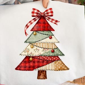 Könnte beinhalten: Weißes Kissenbezug mit einem Patchwork-Weihnachtsbaum-Design. Der Baum besteht aus verschiedenen gemusterten Stoffen in Rot, Grün und Beige, verziert mit goldenen und roten Kugeln und mit einer karierten Schleife gekrönt.