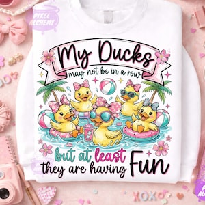 May include: White sweatshirt with a graphic of cartoon ducks in a pool, wearing sunglasses and bows. The text reads "My Ducks may not be in a row but at least they are having Fun."