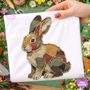May include: A white square fabric featuring a patchwork rabbit design. The rabbit is constructed from various fabric pieces in shades of brown, green, and tan. The text "Pixel Alchemy" is visible in the lower left corner.