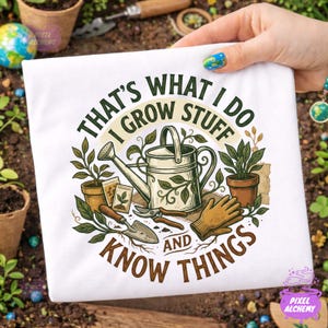 May include: White t-shirt with a gardening-themed graphic. The design includes a watering can, potted plants, gardening tools, and the text "THAT'S WHAT I DO I GROW STUFF AND KNOW THINGS."