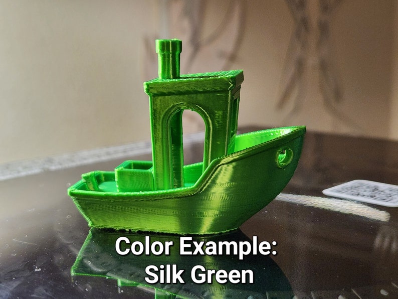 May include: A small green 3D printed model of a boat with a chimney. The boat is sitting on a black surface. Color Example: Silk Green