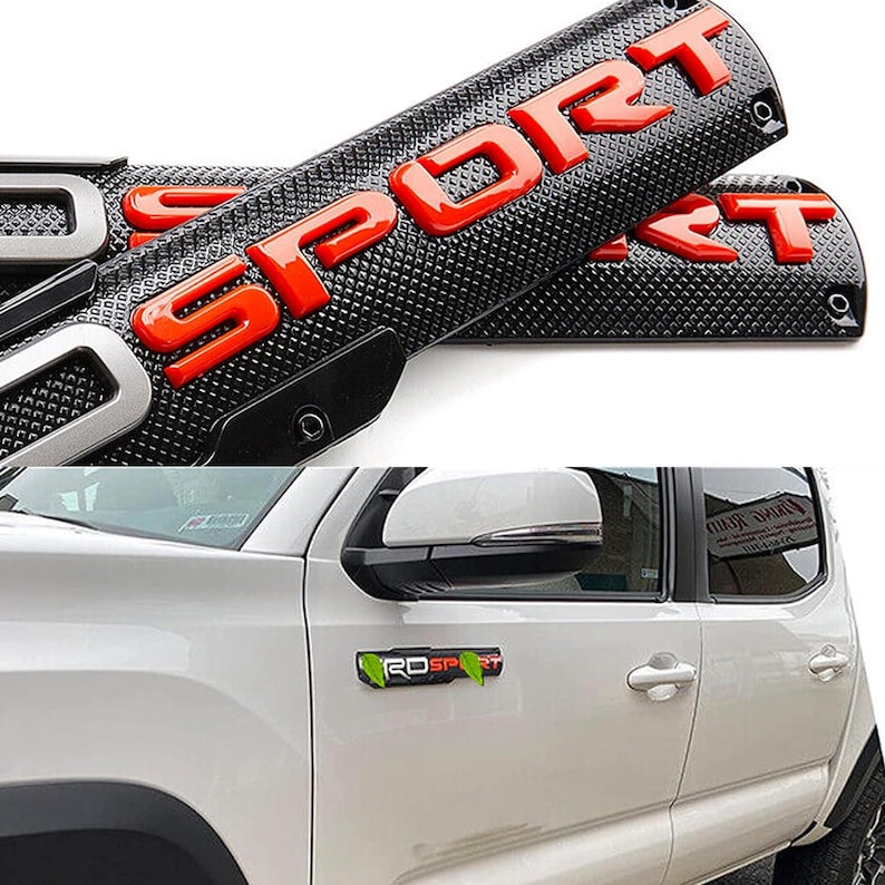 Puede incluir: Un emblema "SPORT" negro y rojo con una superficie texturizada. El emblema se muestra en una camioneta blanca con un emblema "TRD SPORT" verde en el lateral.