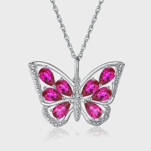 May include: A silver butterfly pendant necklace with a delicate chain. The butterfly design features vibrant pink teardrop-shaped gemstones and is accented with small, clear gemstones along the edges.