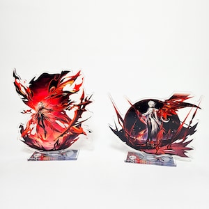 Può includere: Due supporti per personaggi in acrilico con disegni rossi e bianchi. Il primo supporto presenta un personaggio con lunghi capelli bianchi e un abito rosso e nero. Il secondo supporto presenta un personaggio con lunghi capelli bianchi e un abito bianco. Entrambi i supporti hanno uno sfondo nero.