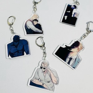 May include: A collection of acrylic keychains featuring anime-style illustrations. Each keychain has a silver-colored metal ring and depicts male figures in various poses and outfits. The illustrations use a palette of blues, blacks, and skin tones.