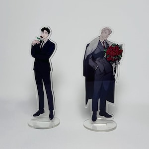 May include: Two acrylic stand-up figures of men in suits. The man on the left is holding a single red rose. The man on the right is holding a bouquet of red roses.